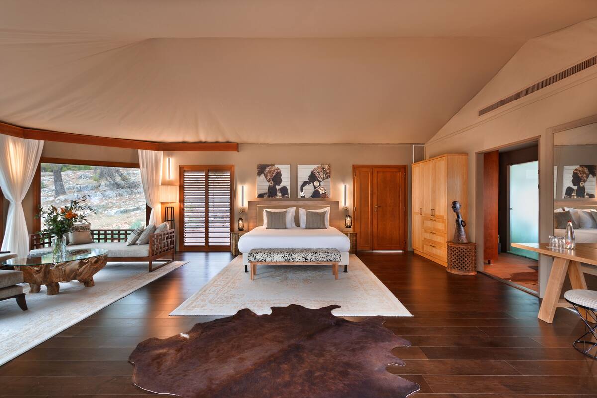 A spacious bedroom with a large bed, wooden furniture, and a view of the outdoors.