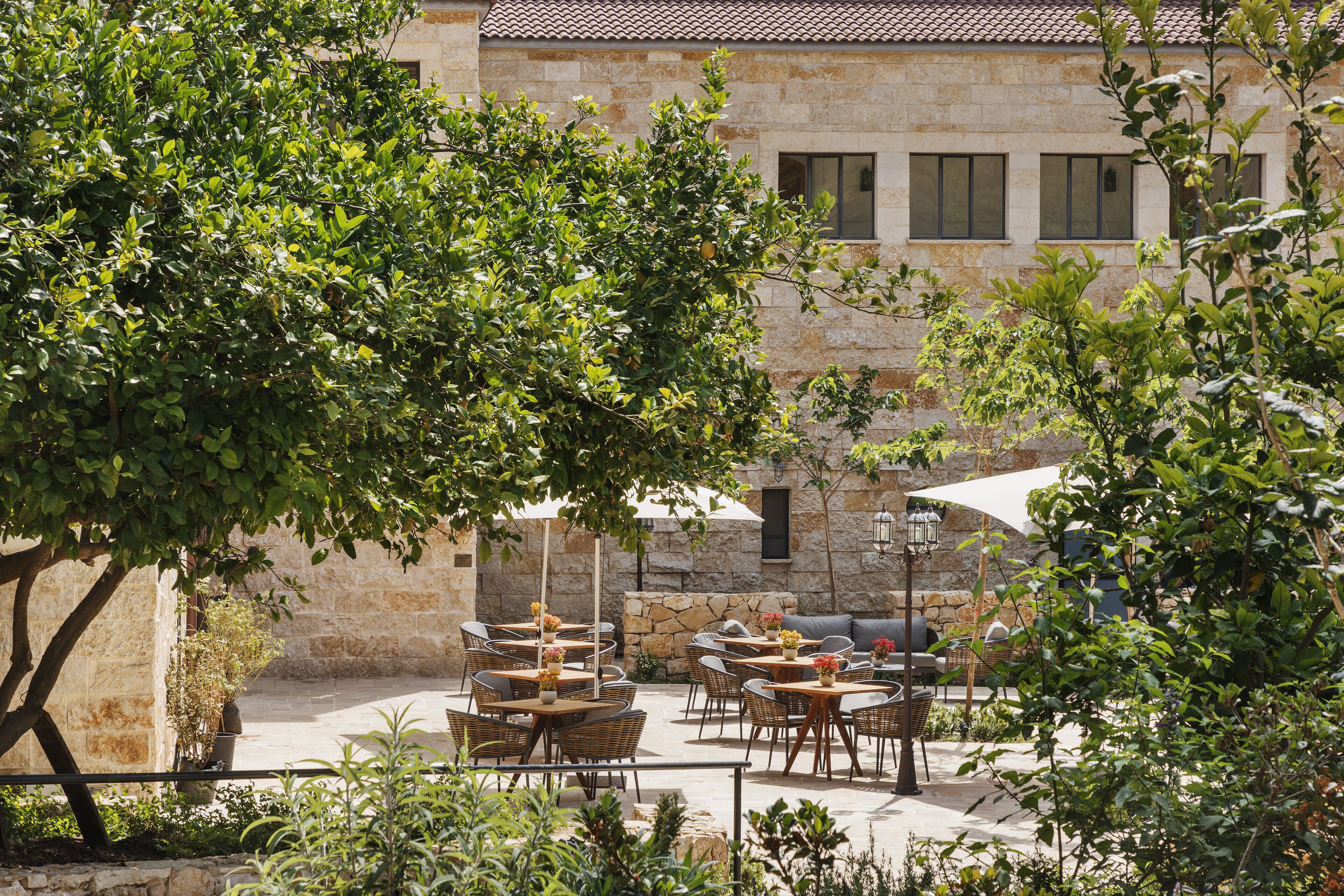 Une terrasse extérieure avec des murs en pierre, des meubles en osier et des parasols.