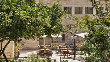Une terrasse extérieure avec des murs en pierre, des meubles en osier et des parasols.