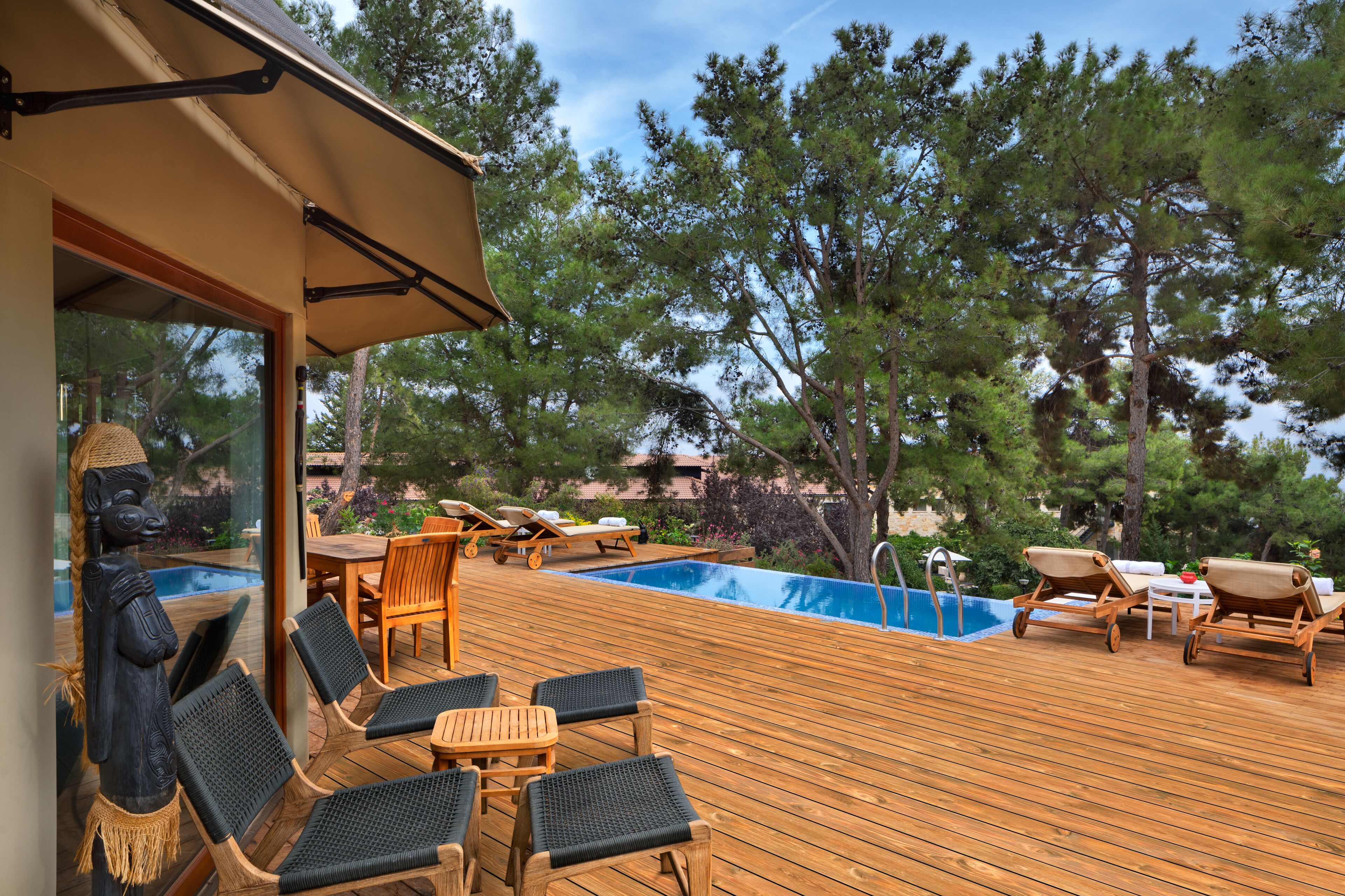 Una terraza de madera con sillones de descanso y una piscina.