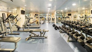 Un gimnasio con diversos equipos de ejercicio, como cintas de correr, máquinas de pesas y mancuernas.