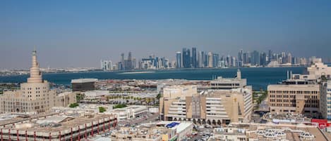 A cityscape with a prominent mosque, modern buildings, and a waterfront.
