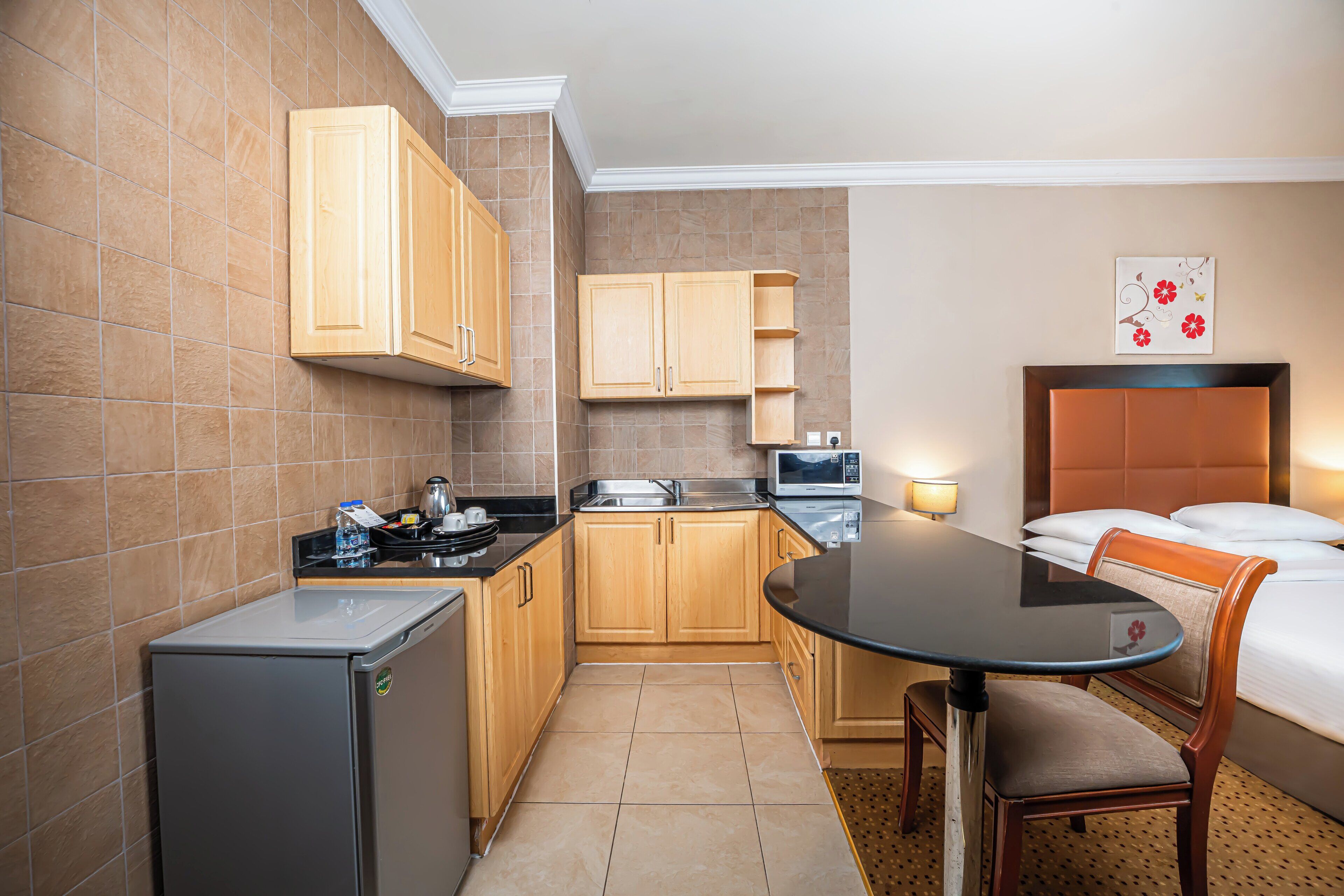Habitación de hotel compacta con kitchenette, una cama con cabecera, una mesa de comedor y una silla.