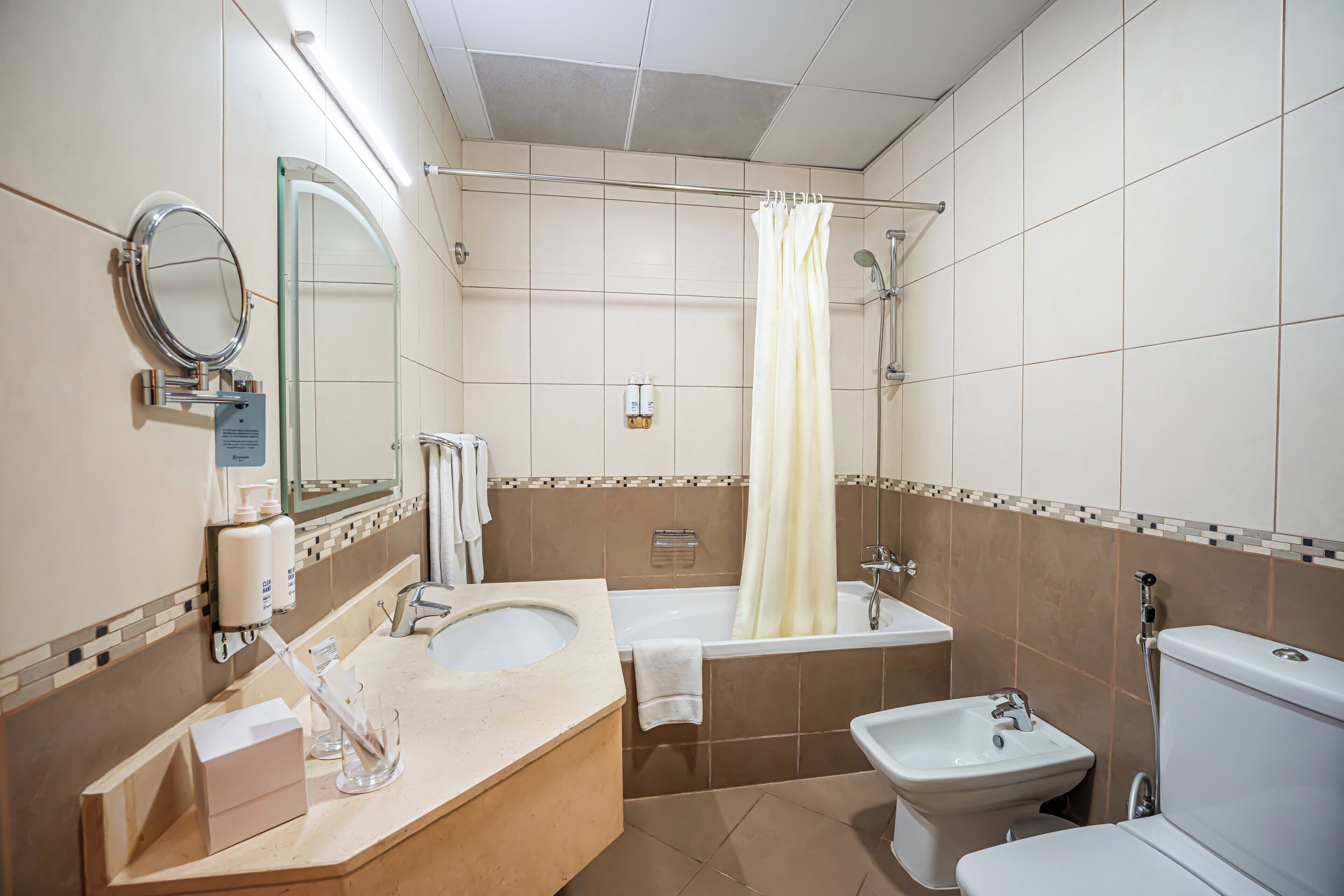 A bathroom with a sink, bidet, bathtub, and toilet.