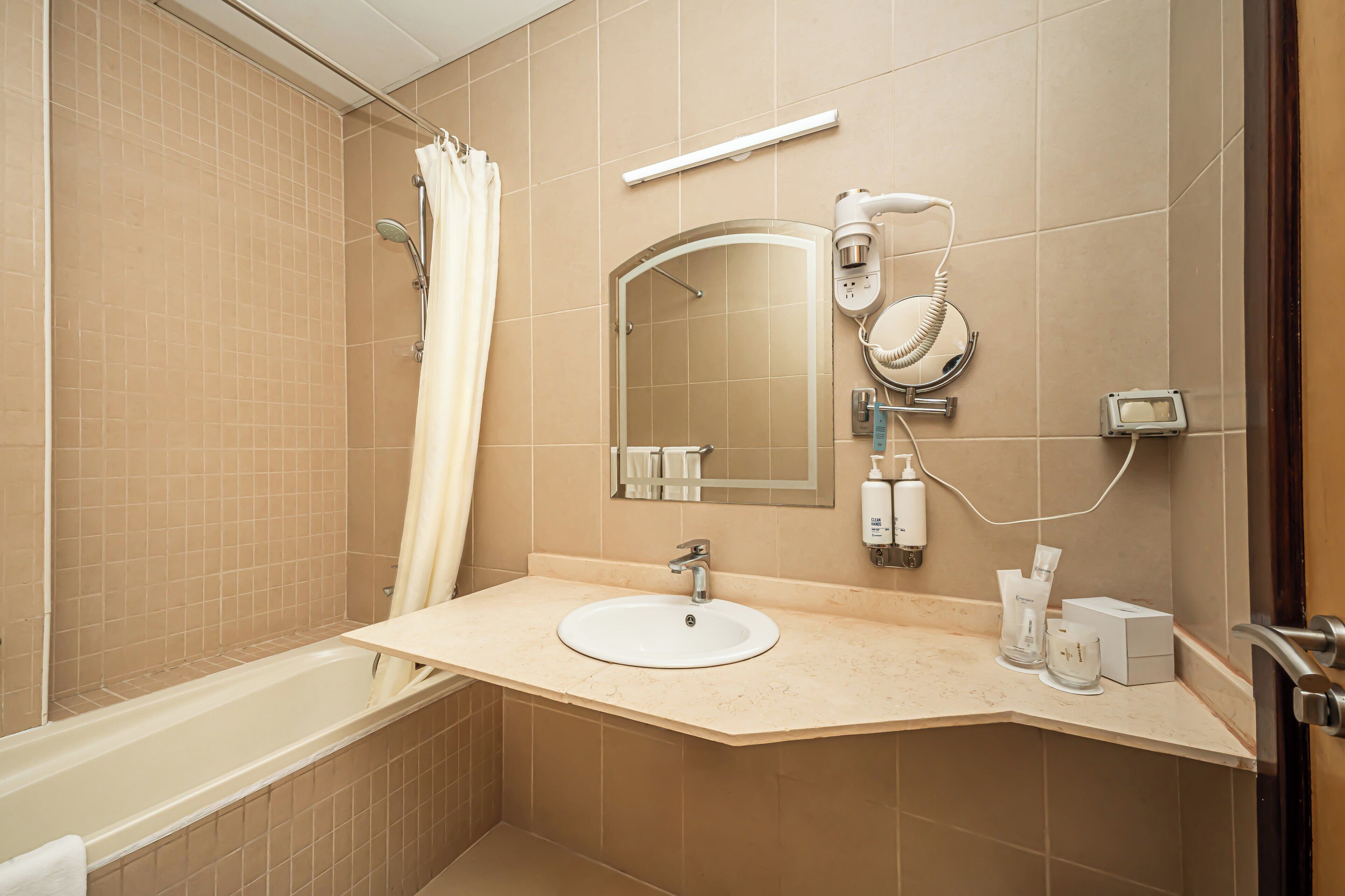 A modern bathroom with a bathtub, a sink, a mirror, and a hairdryer.