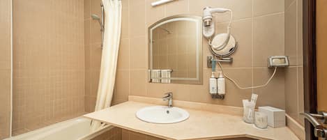 A modern bathroom with a bathtub, a sink, a mirror, and a hairdryer.