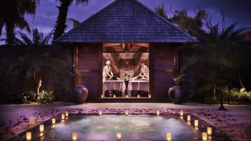 A spa with a massage table, a stone wall, and a water feature with candles.