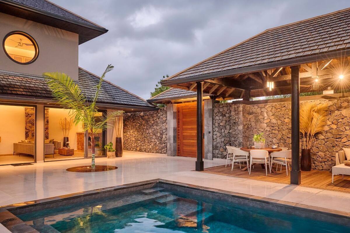 A modern house with a swimming pool, stone walls, and a covered patio area.
