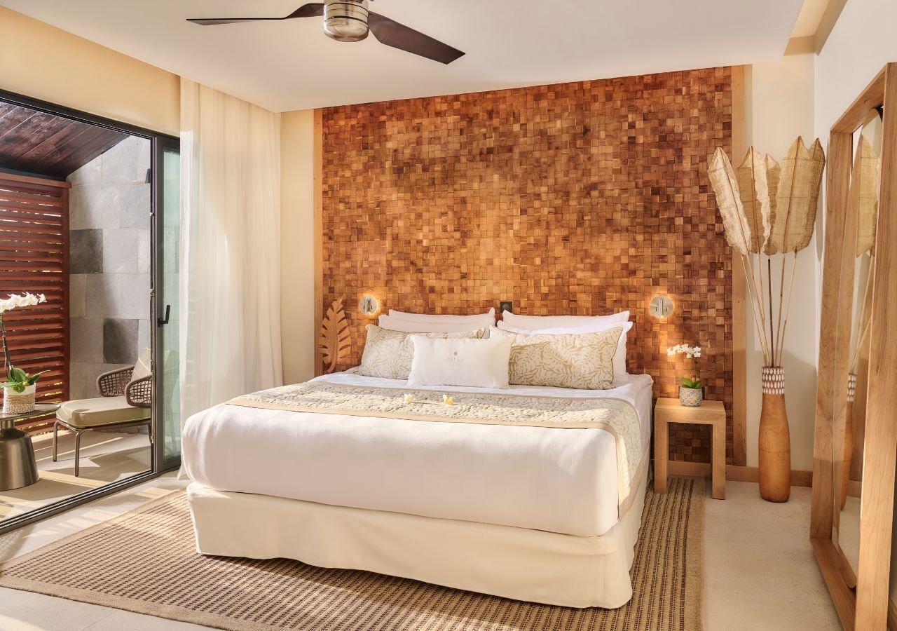 Een moderne slaapkamer met een groot bed, een houten hoofdbord, een klein nachtkastje en een grote spiegel.