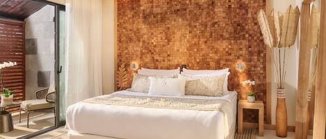 A modern bedroom with a large bed, a wooden headboard, a small bedside table, and a large mirror.