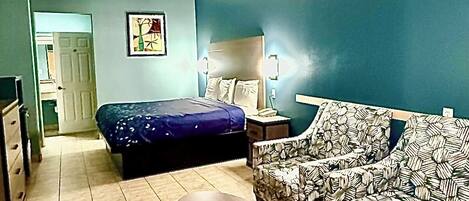 A room with a bed, a sofa, a table, and a painting on the wall.
