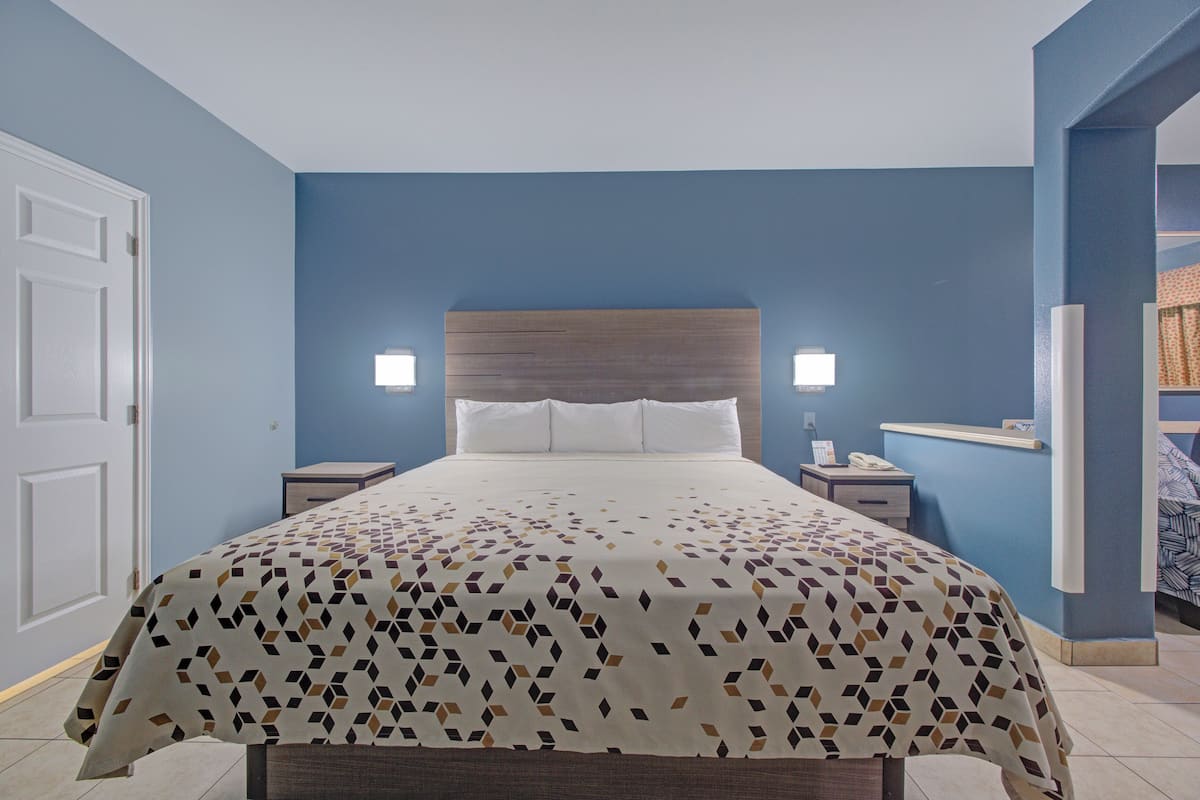 Une chambre d’hôtel avec un lit, des tables de chevet et une tête de lit.