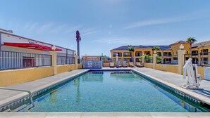 A swimming pool with a 3 FT depth marking, surrounded by a fence, with a building in the background. - Weslaco Inn Weslaco/Mercedes (Weslaco)