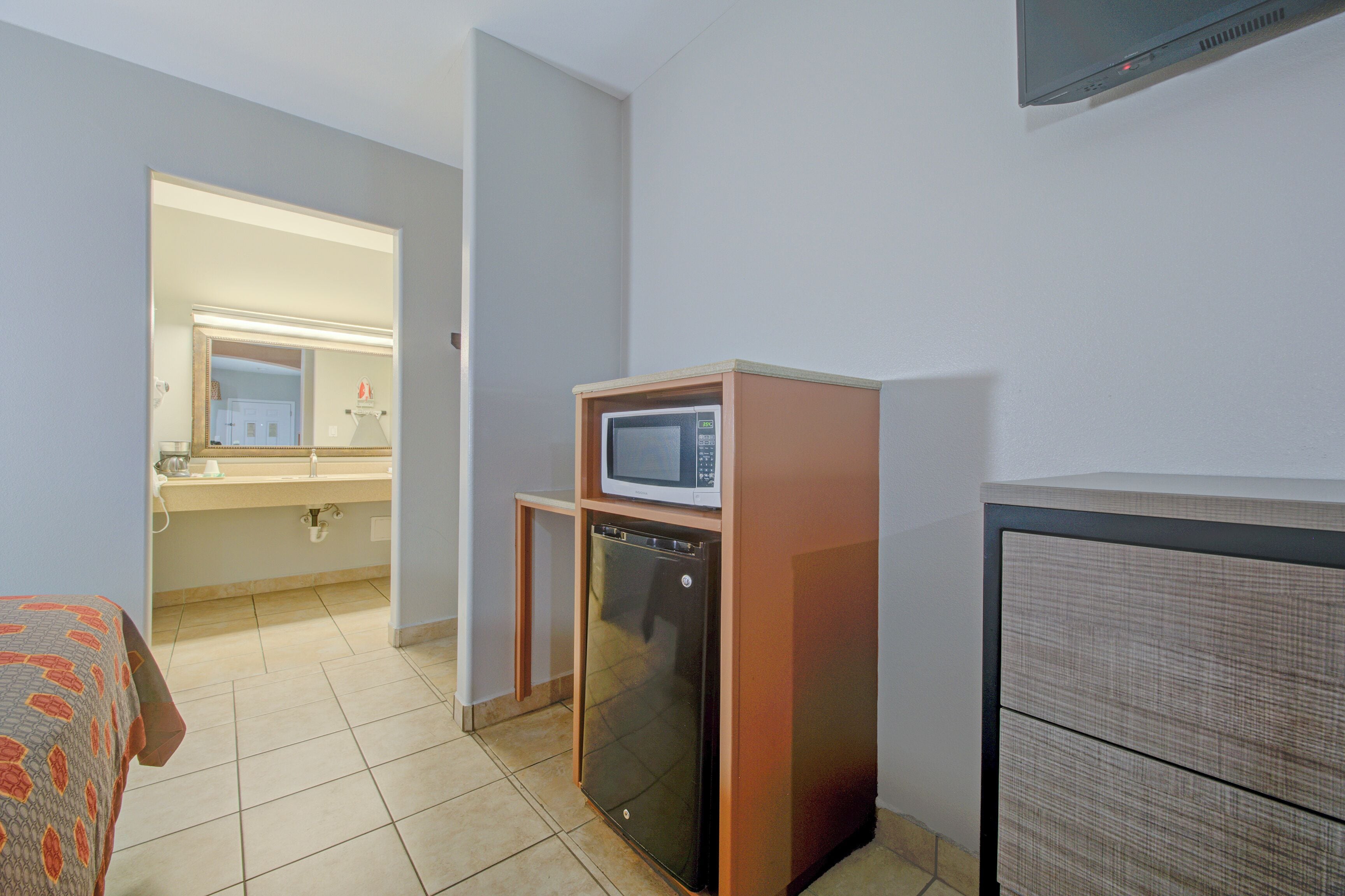 A compact kitchenette with a microwave, refrigerator, and a small cabinet.