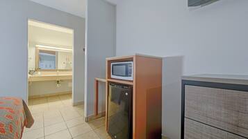 A compact kitchenette with a microwave, refrigerator, and a small cabinet.