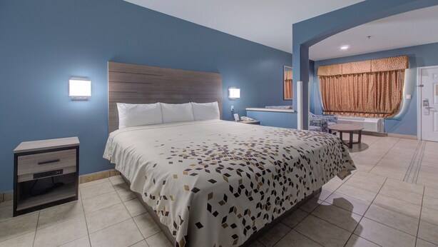 A hotel room with a bed, bedside table, and a small table with a chair. - Weslaco Inn Weslaco/Mercedes (Weslaco)