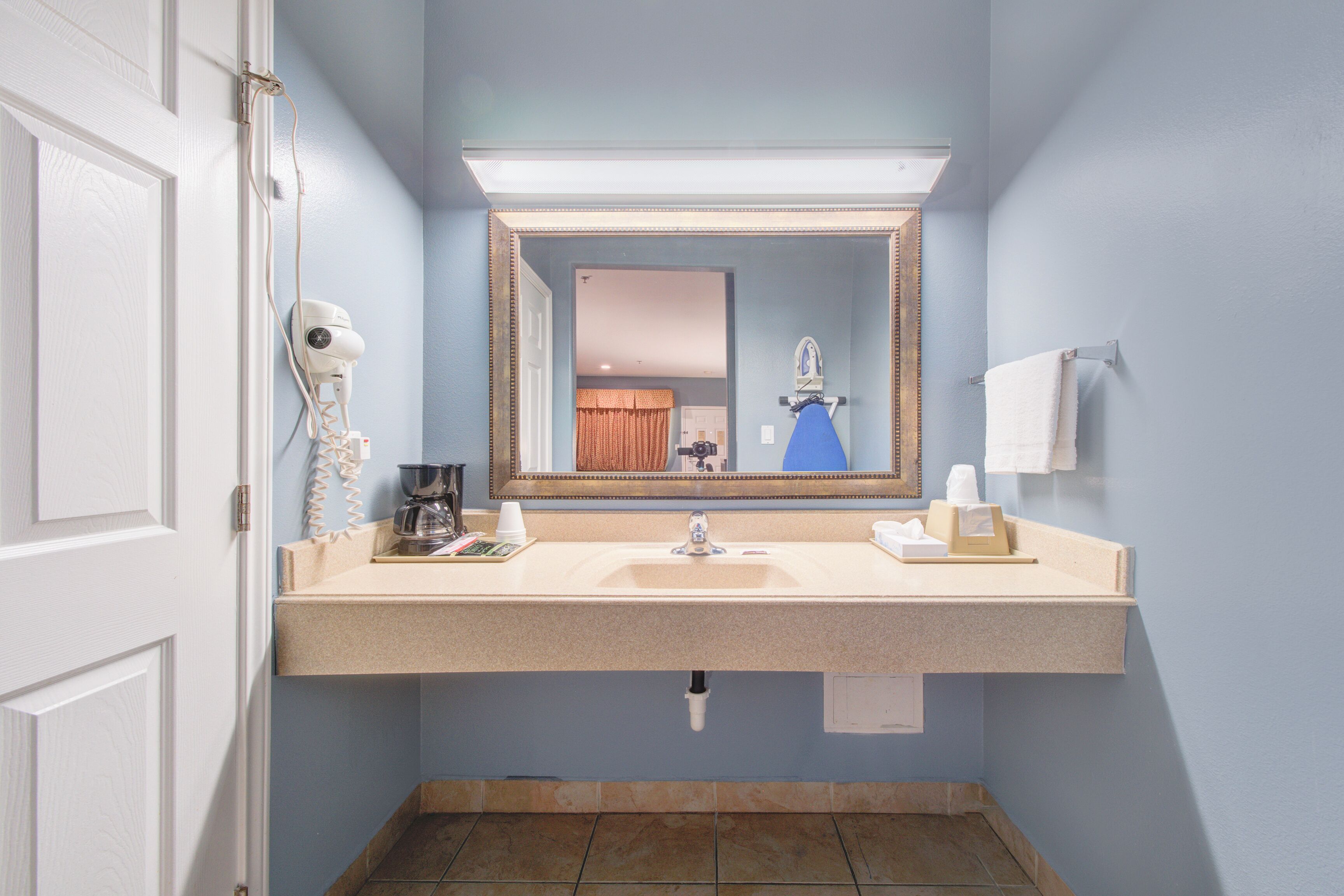 A bathroom with a sink, mirror, towel rack, and a hairdryer on the counter.