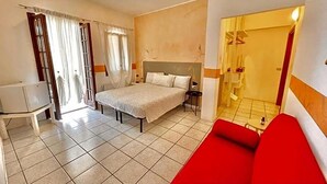 A bedroom with a bed, a red sofa, a small table, and a white chair. - Vittoria (Toscolano Maderno)