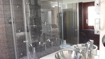 A modern bathroom with a glass-enclosed shower, a large sink, and a mirror.