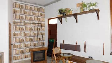 Una habitación con chimenea, estanterías, un banco de madera y una pequeña mesa.