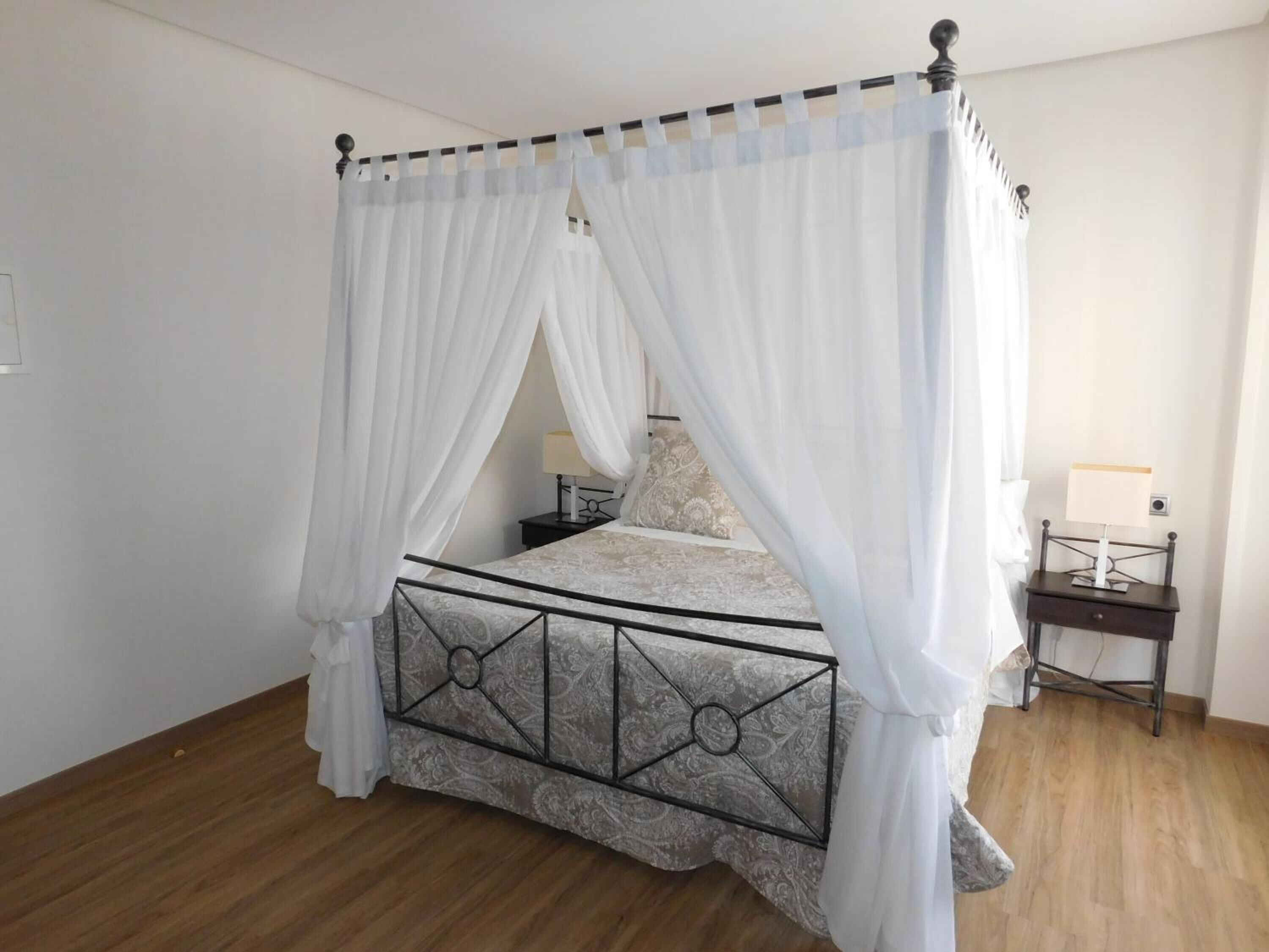 Un lit à baldaquin, une table de chevet avec une lampe et une petite table de nuit avec une lampe.