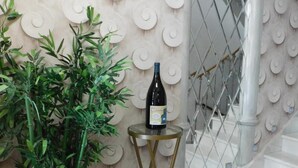 A modern interior with a spiral-patterned wall, a potted plant, a wine bottle on a small table, and a staircase with a glass railing. - Hospedium Hotel Cañitas Maite Boutique (Casas-Ibanez)