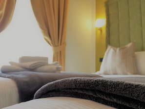 Une chambre d’hôtel avec un lit bien fait, une tête de lit verte et une lampe fixée au mur.