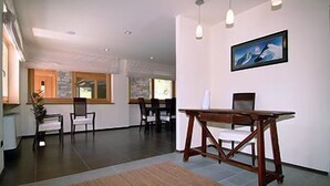 A spacious room with a dining table and chairs, a painting on the wall, and a view of the outdoors through large windows. - Nordend (Gressoney-la-Trinite)