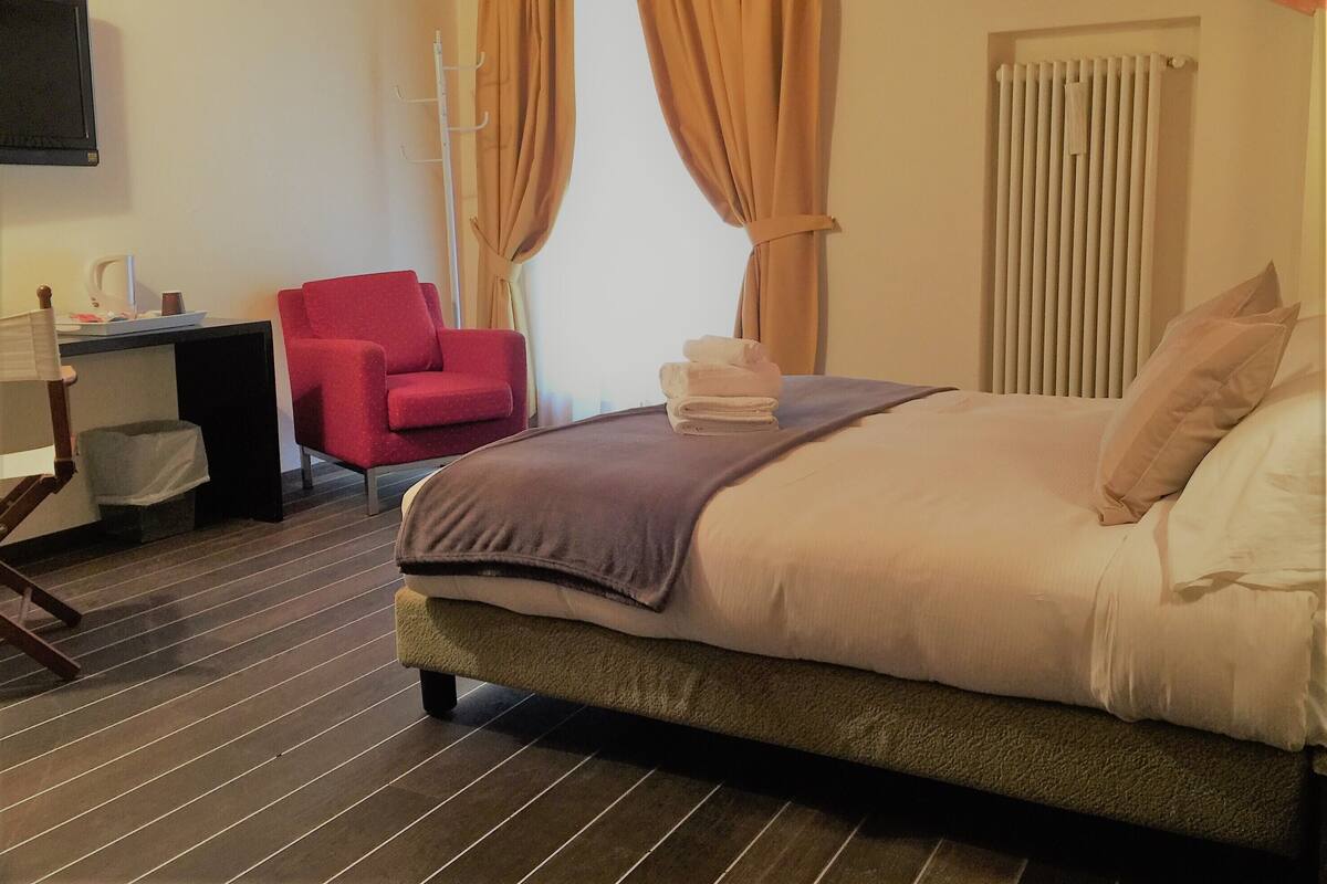 Una habitación de hotel con cama, escritorio, silla y televisor.