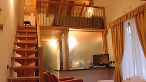 A hotel room with a wooden staircase, a bed with neatly folded towels, a desk with a computer, and a window with curtains. - Nordend (Gressoney-la-Trinite)