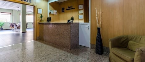 A hotel reception area with a counter, a sign for the cafeteria, and a reception desk.