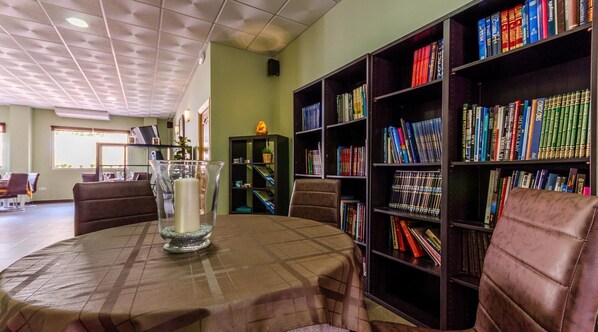 Una biblioteca con una mesa redonda, sillones de cuero y estanterías llenas de libros.