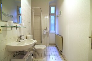 A compact bathroom with a sink, toilet, and glass shower enclosure. - Apartment Berlin 1 (Berlin)