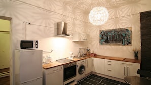 A compact kitchen with a microwave, oven, washing machine, and coffee maker. - Apartment Berlin 1 (Berlin)