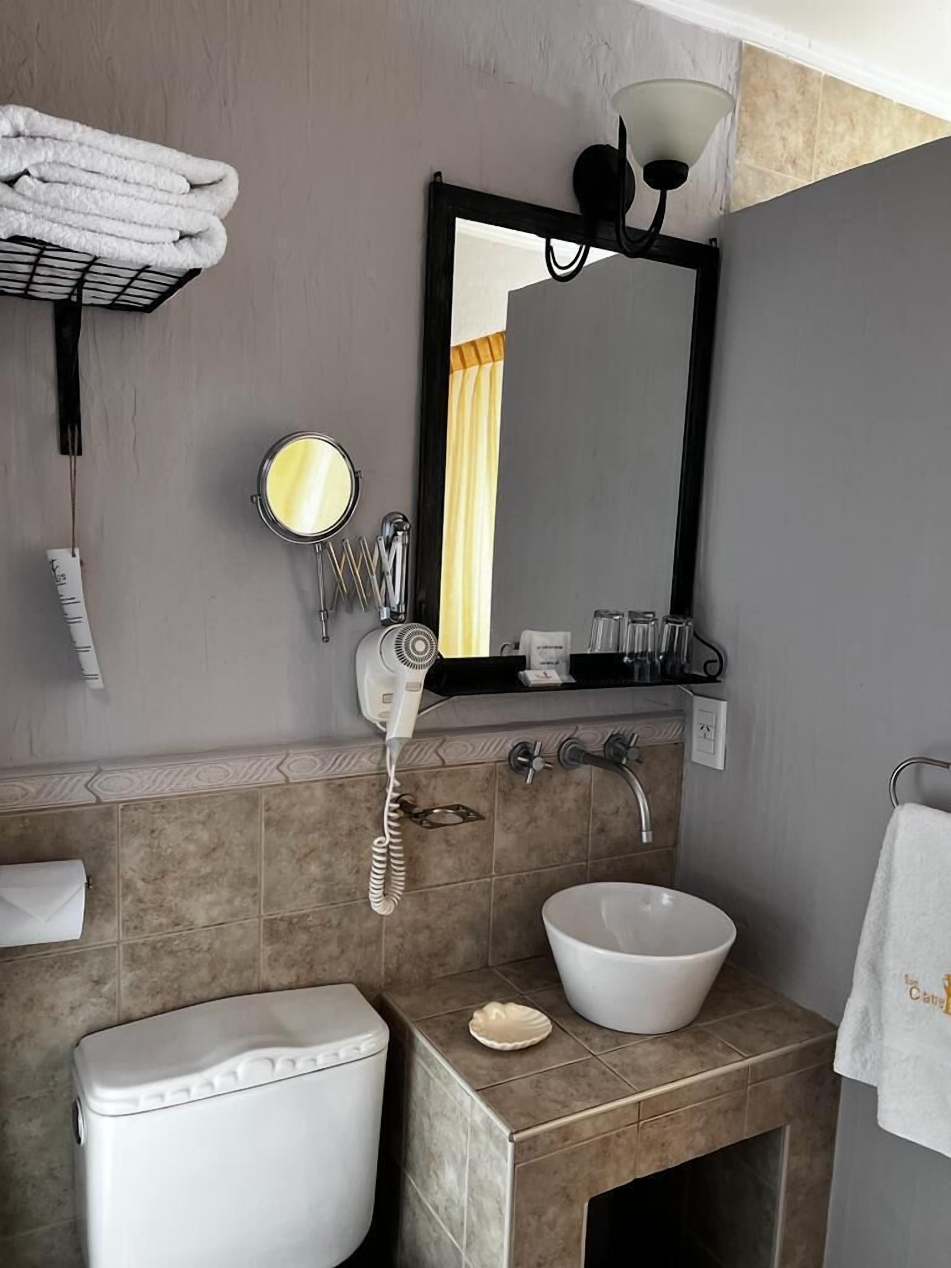 Un baño con inodoro, lavamanos y perchero para toallas.