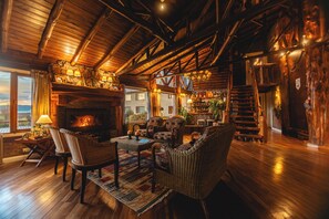 A cozy lodge interior with a fireplace, wooden furniture, and a staircase leading to an upper level. - Los Canelos (El Calafate)