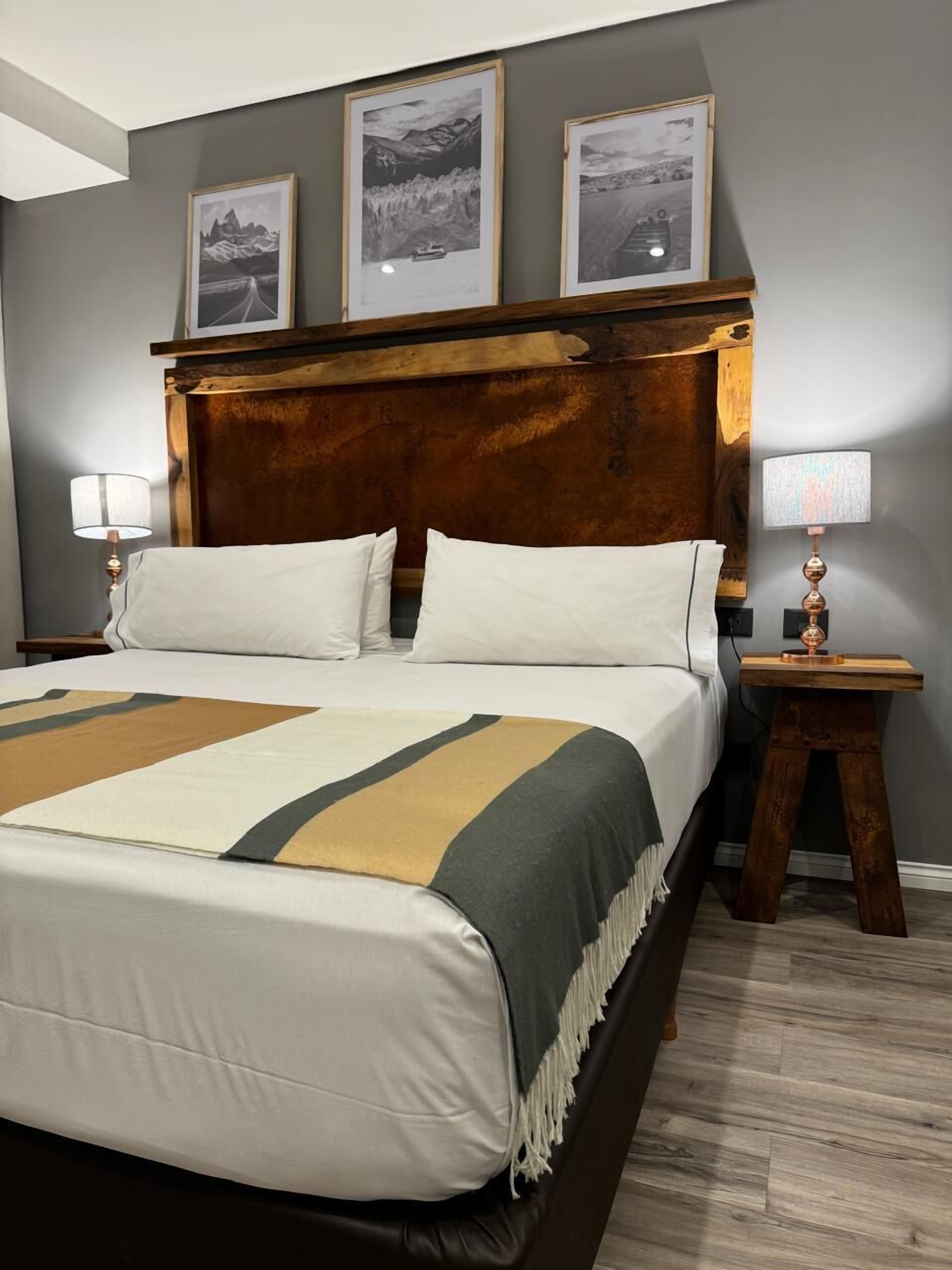 A neatly made bed with a striped blanket, a wooden headboard, and a nightstand with a lamp.