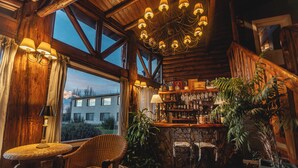 Un interno rustico con camino in pietra, mobili in legno e un'area bar con diversi tipi di bottiglie.