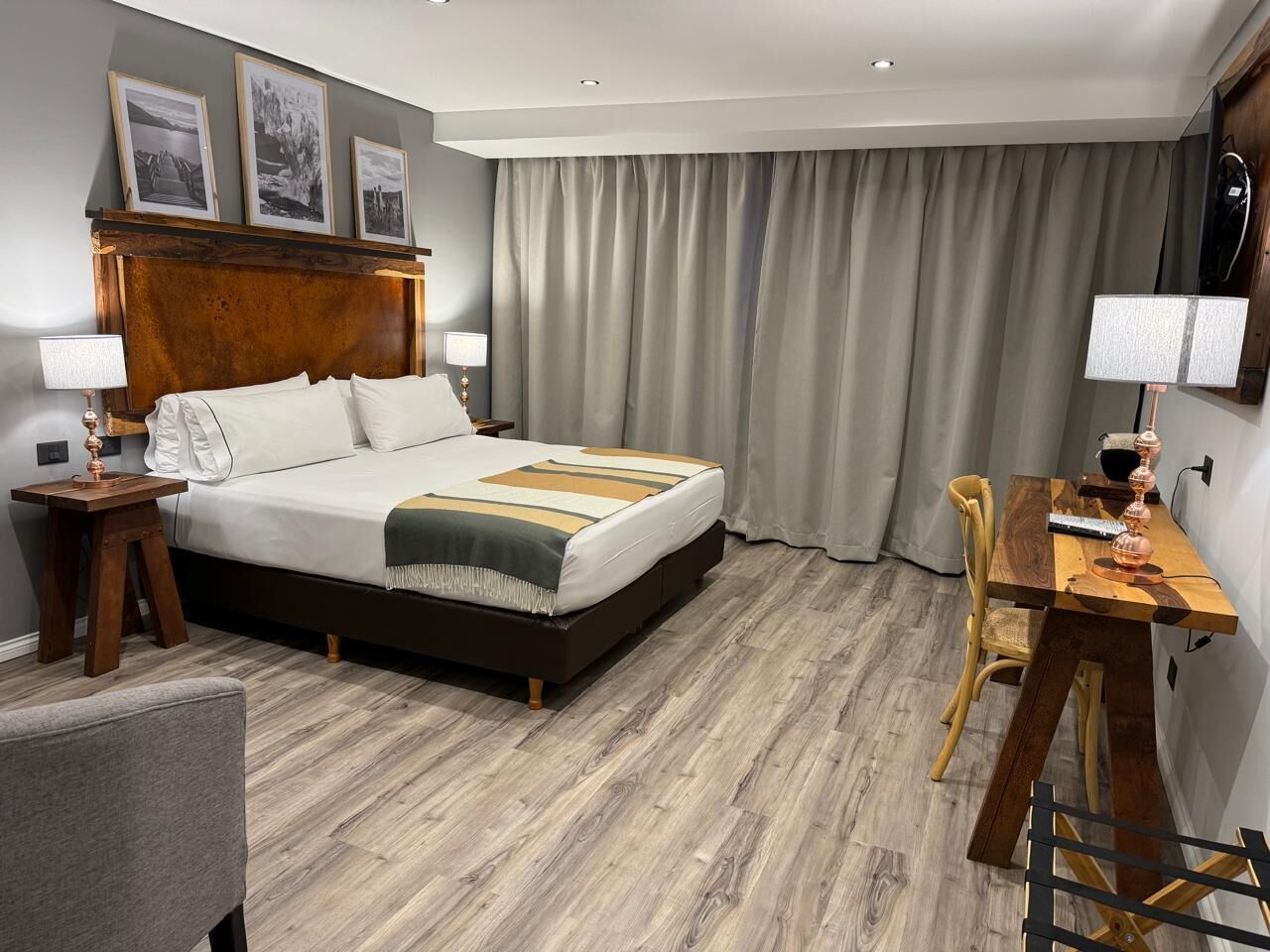 Quarto de hotel com uma cama grande, uma escrivaninha de madeira e uma mesa de jantar.