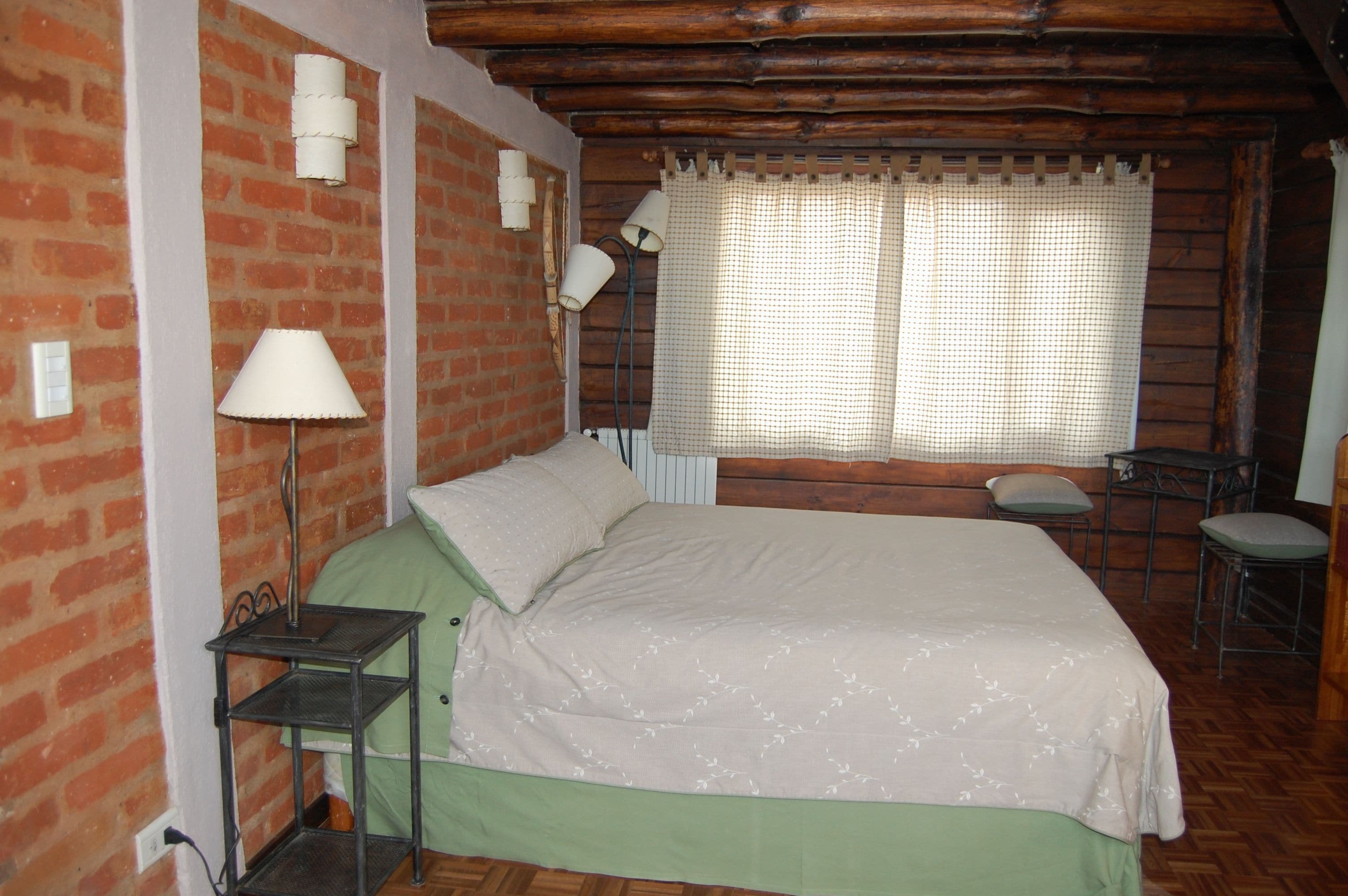 A room with a bed, a nightstand, a table, and a chair.
