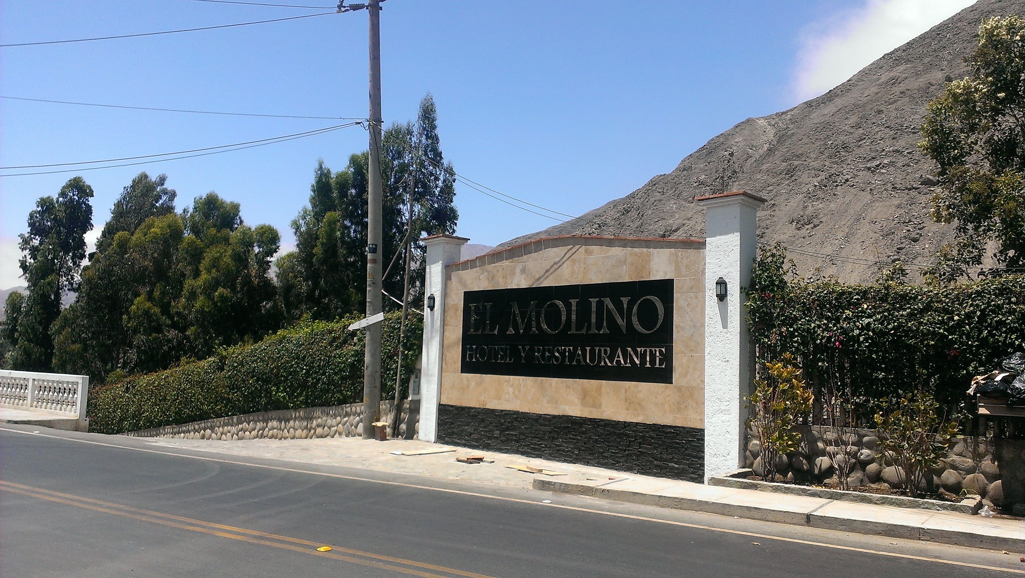 Placa do Hotel & Restaurante El Molino, com um muro de pedra e uma montanha ao fundo.