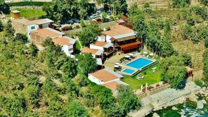 Vue aérienne d’une station balnéaire comprenant plusieurs villas, une piscine et une côte rocheuse.