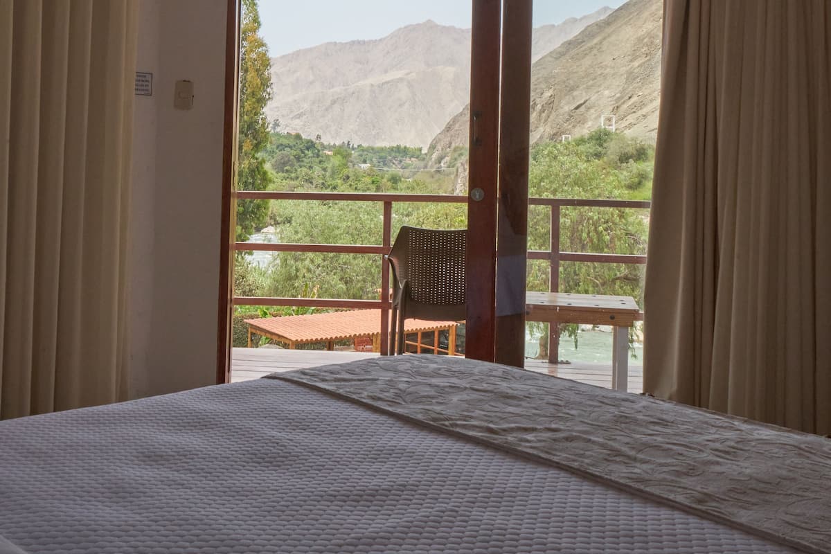 Ein Hotelzimmer mit Bett, Deckenventilator und Bergblick durch ein großes Fenster.