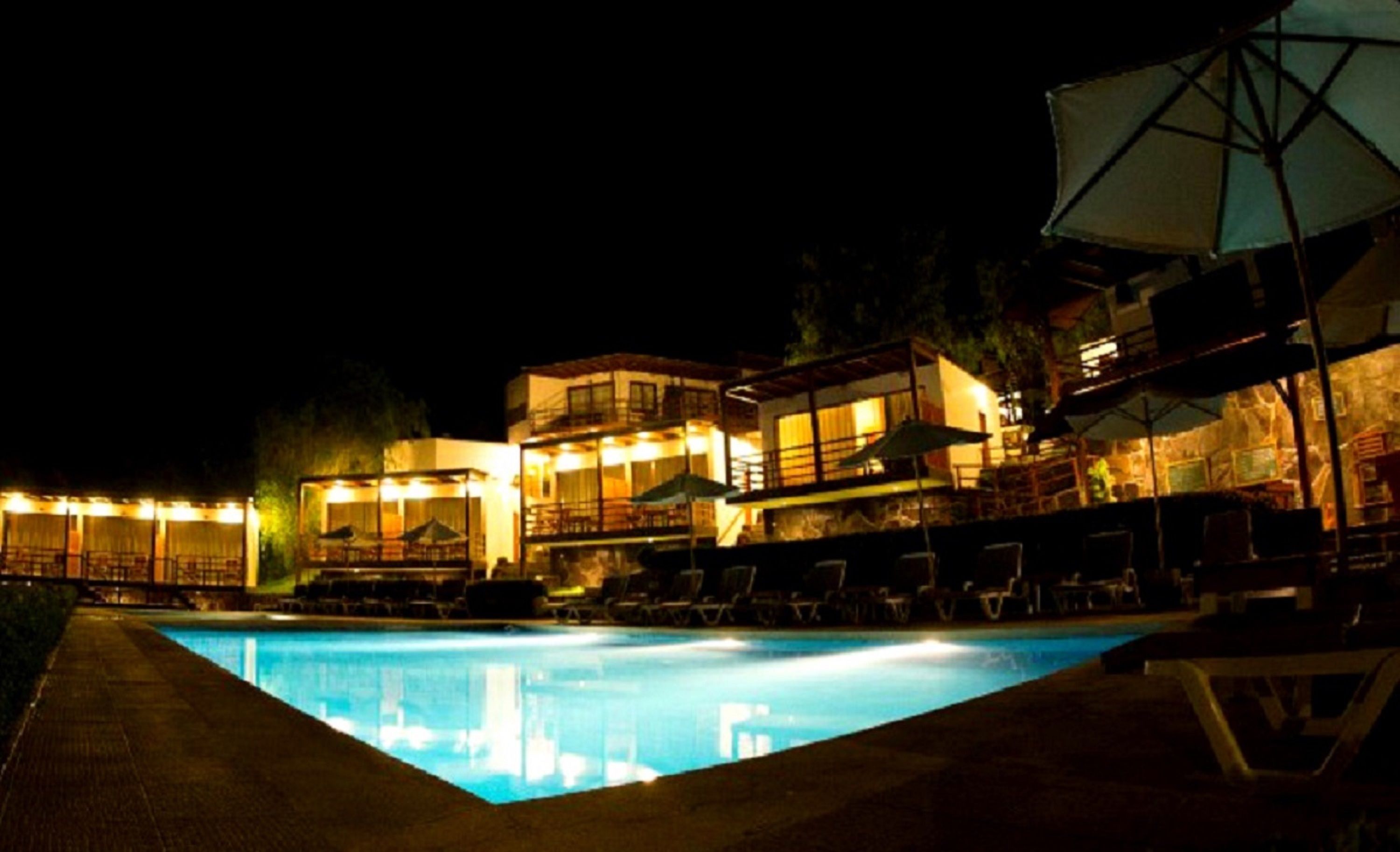 Una piscina al aire libre, sombrillas, sillones reclinables de piscina