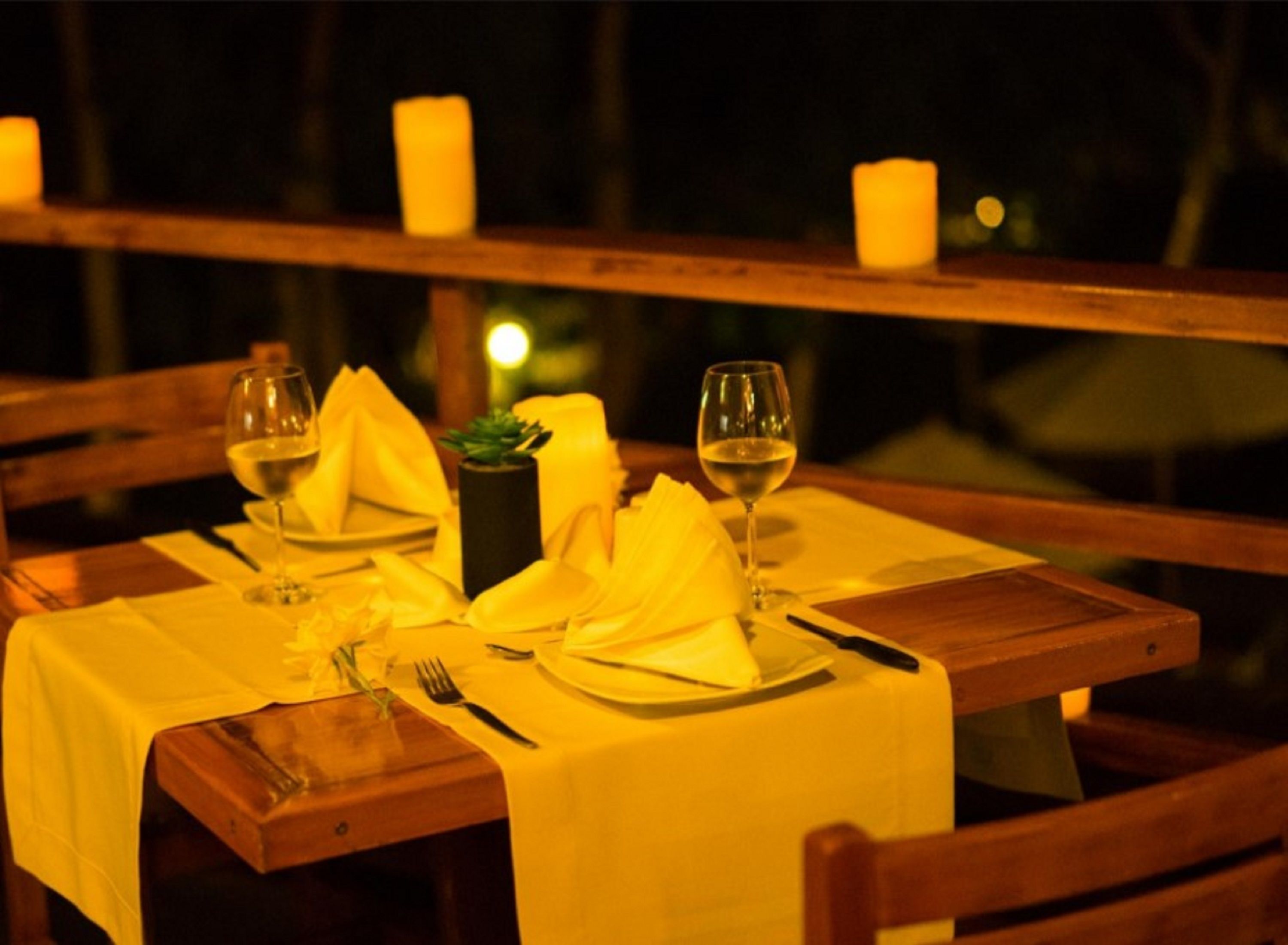 A dining table set with white tablecloth, candles, and wine glasses.