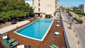 A hotel with a swimming pool, outdoor seating, and a building with 'ALBA' on the facade. - Hotel Alba (Misano Adriatico)