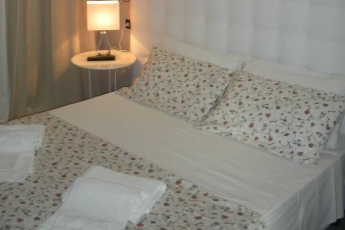 Une chambre d’hôtel avec un lit, une lampe de chevet et un rideau.