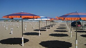 A beach with multiple umbrellas and poles, suggesting a beachside location. - Hotel Alba (Misano Adriatico)