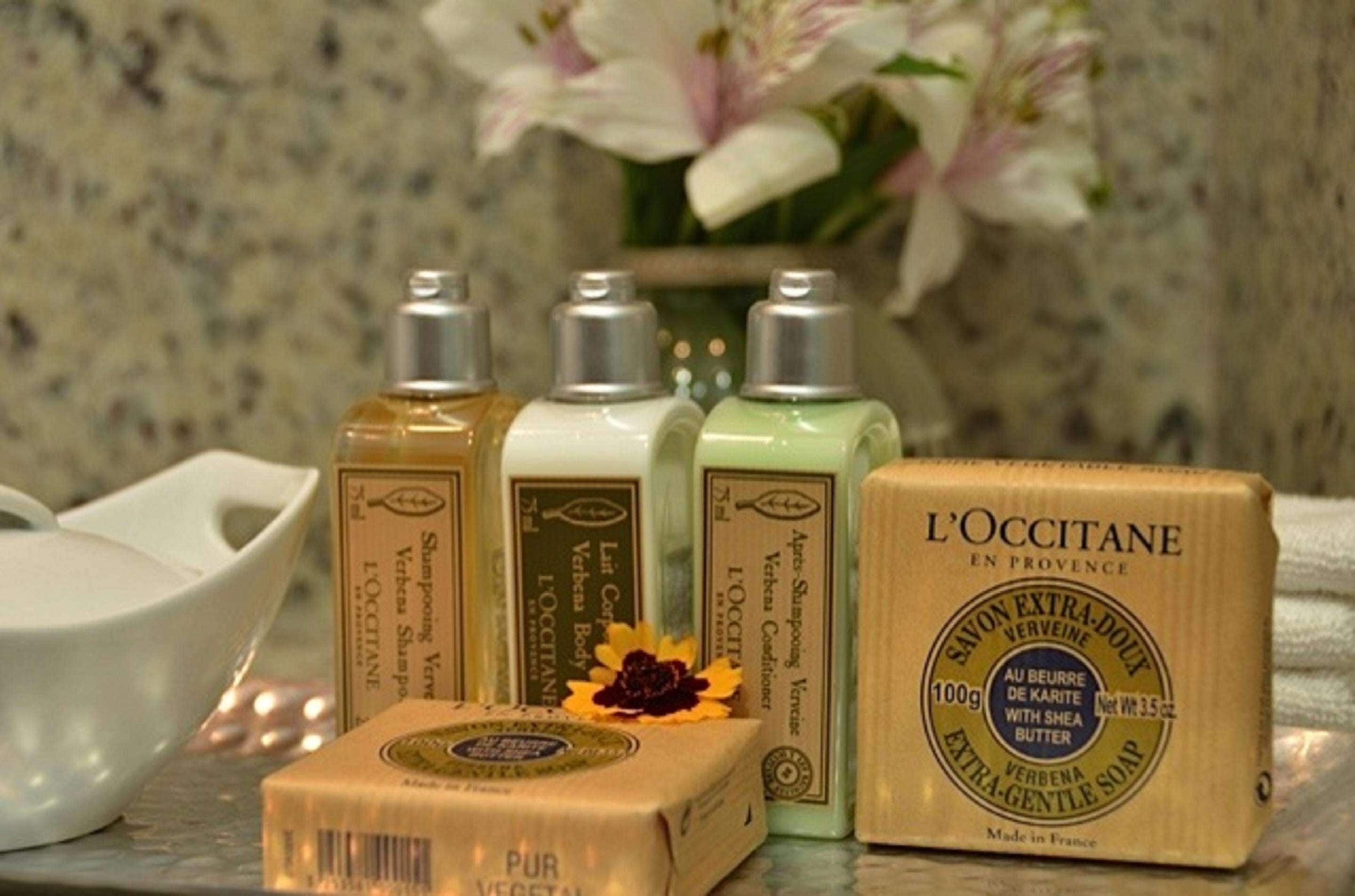 Un juego de artículos de tocador L'OCCITANE que incluye una barra de jabón, tres botellas de champú y un cuenco.