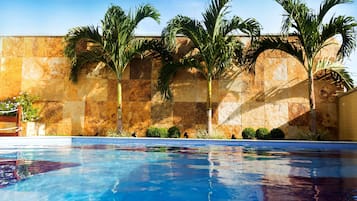 Una piscina al aire libre, sombrillas, sillones reclinables de piscina